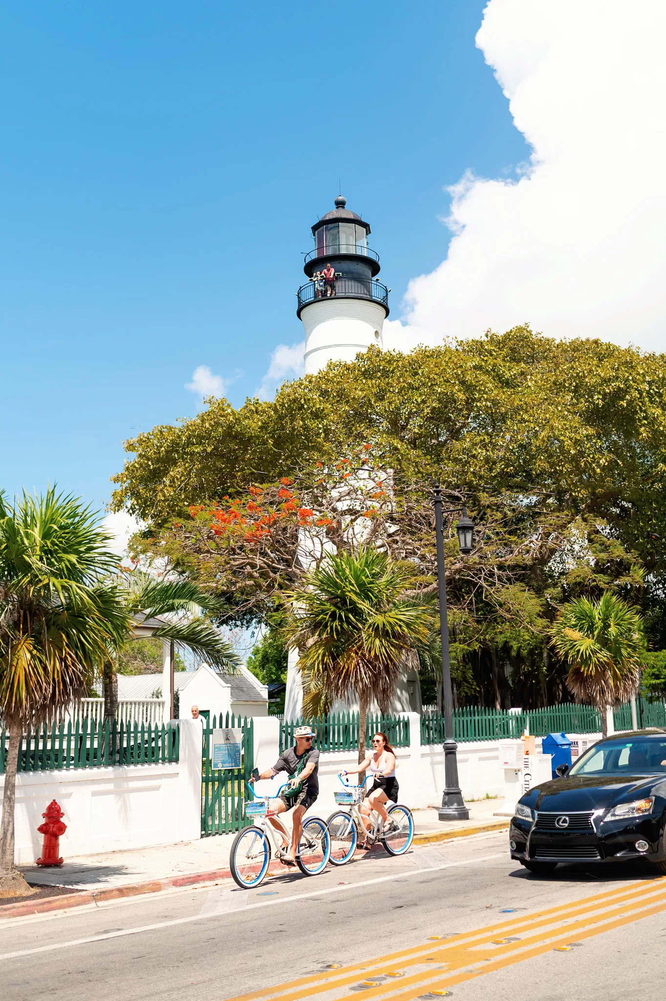 Two people riding bikes in Key West, Florida with the lighthouse in the background