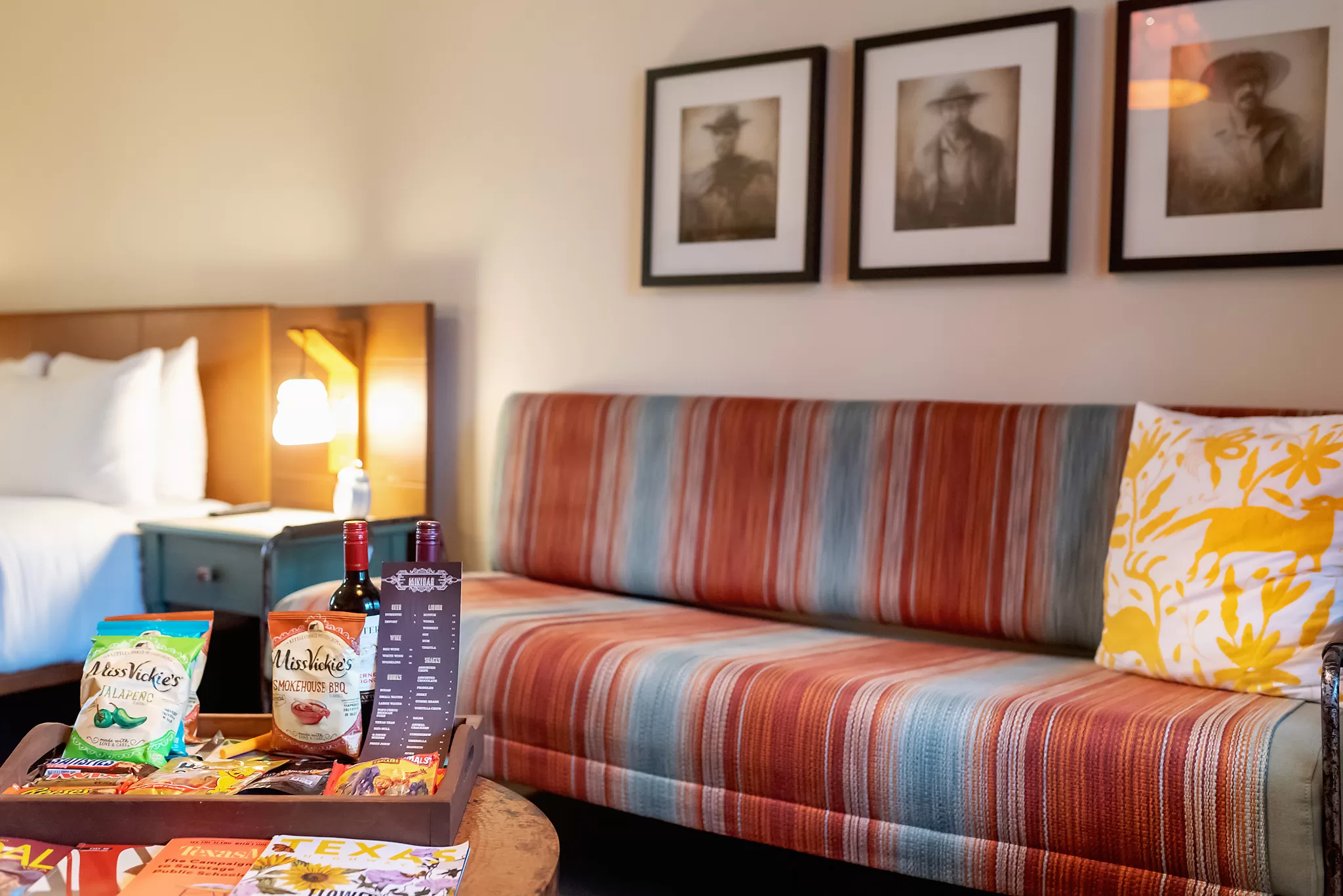 King Room at the Texican Court. Photo shows the couch with brightly colored textiles on it and some mini bar style snacks for purchase