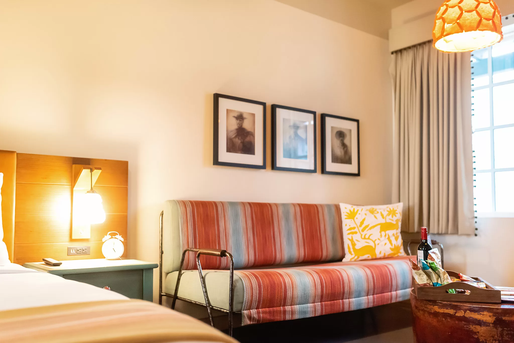 Couch covered in bright textiles with three western photos hung above it in a guestroom at the Texican Court Hotel