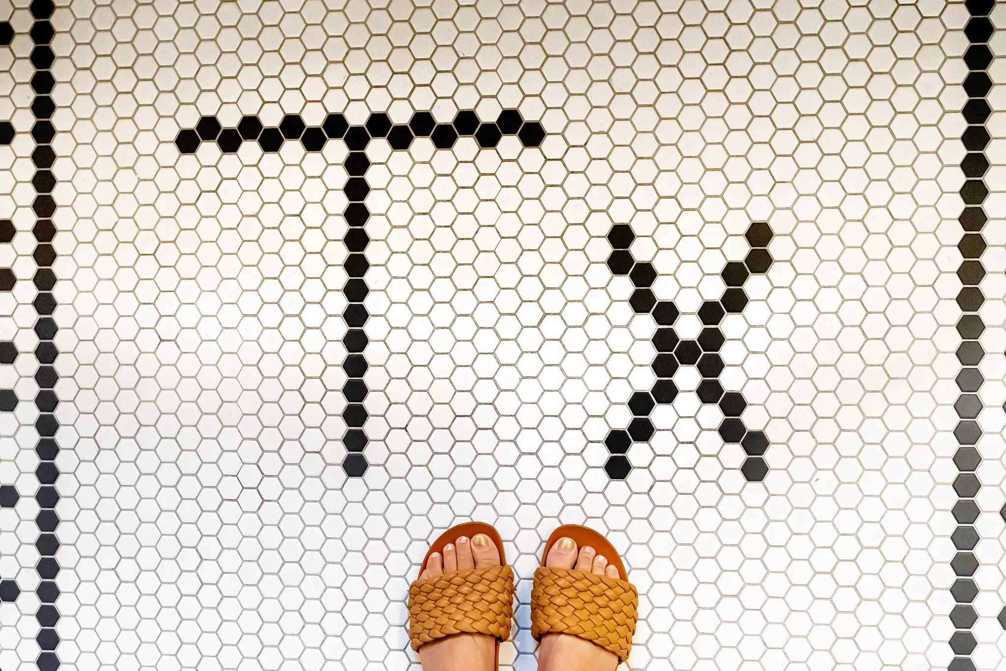 Tile that says Tx on the floor in the bathroom in a room at the Texican Court Hotel