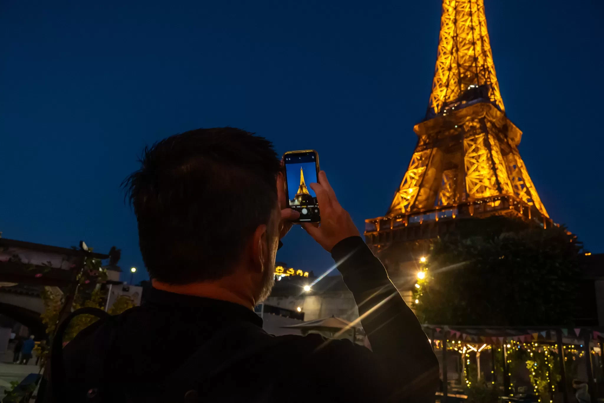 Man taking a photo of the Eiffel Tower at night