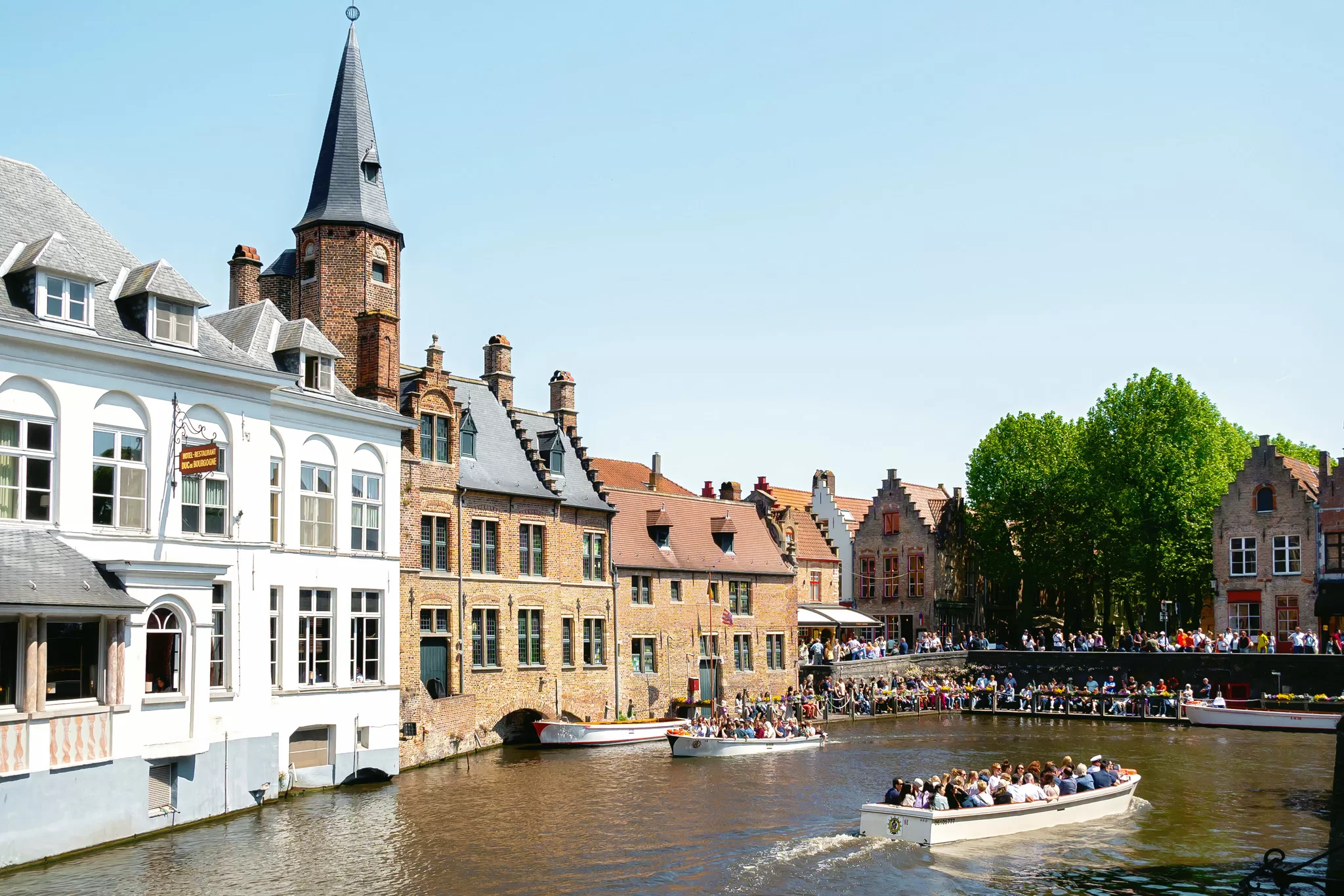historic Buildings and people waiting in line for a canal tour in Brugges Belgium
