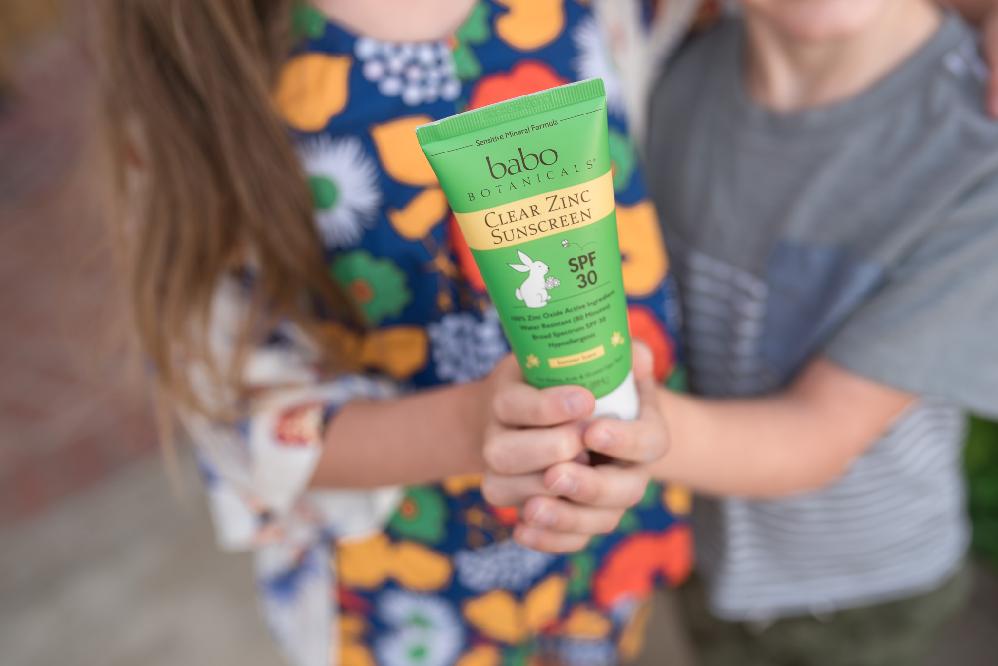 Kids applying Babo Botanicals clear zinc sunscreen 