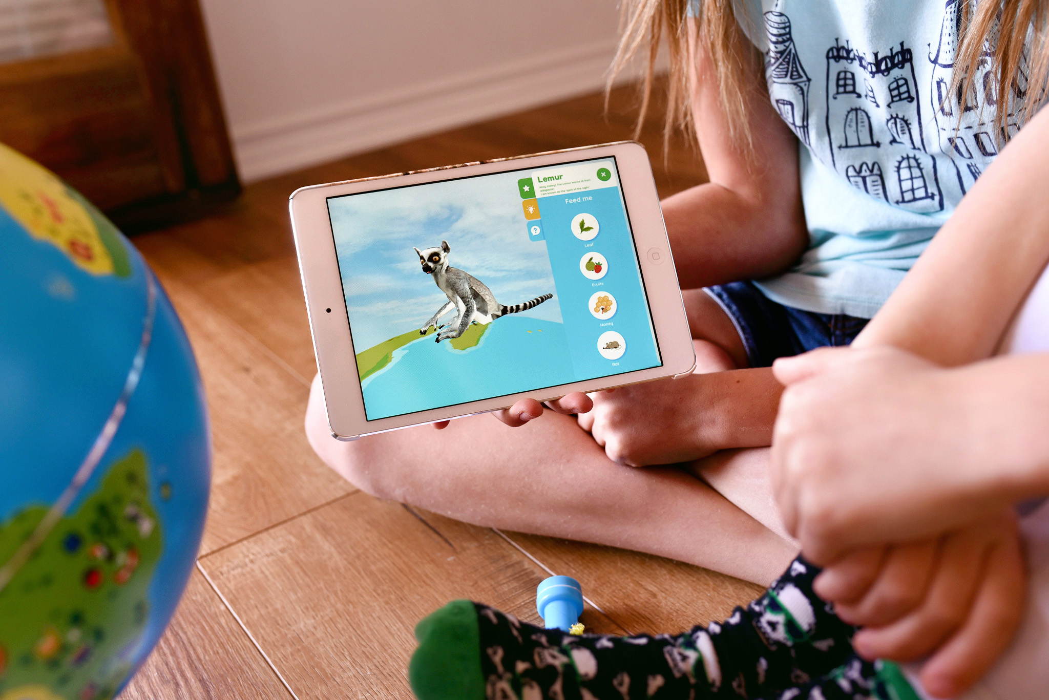 Orboot review - image shows a girl holding an ipad learning about animal on the Orboot Interactive Globe