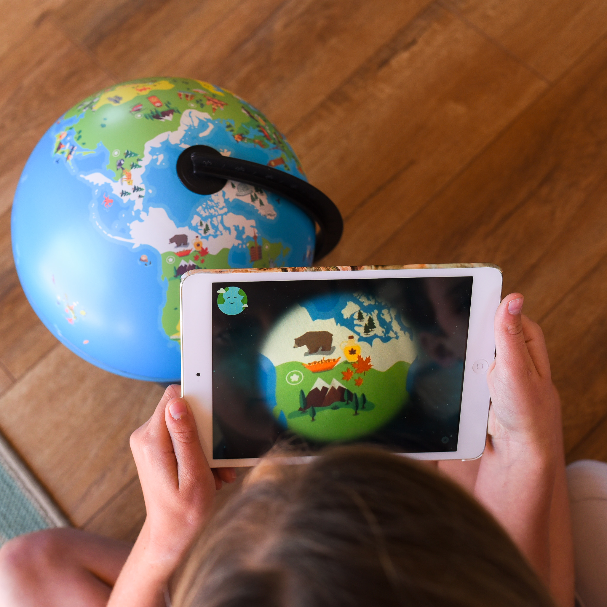 Orboot review - image shows a girl holding an ipad learning about animalson the Orboot Interactive Globe