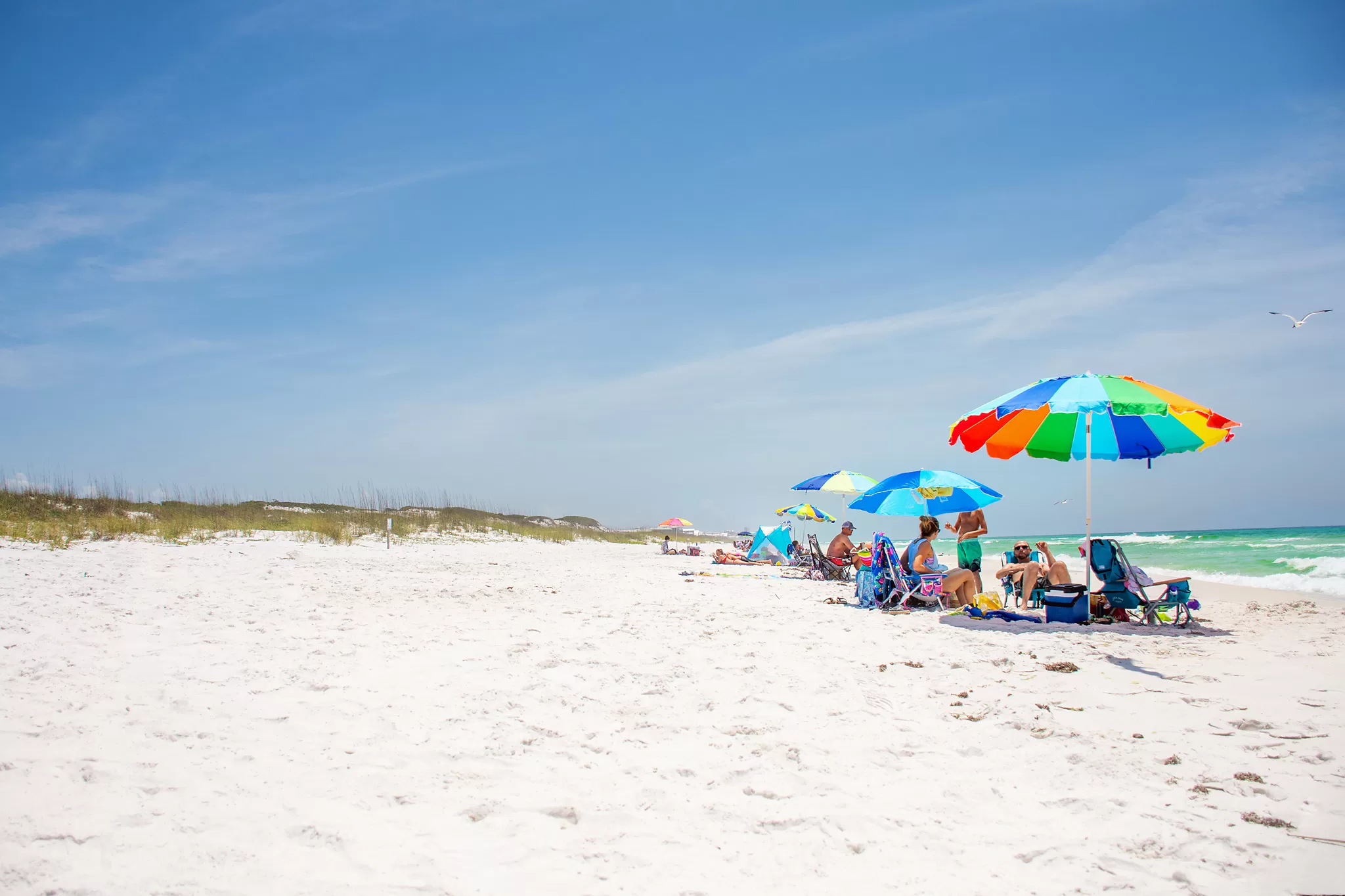 30a day trips travel guide with photo of brightcolored beach umbrellas on white sand beaches