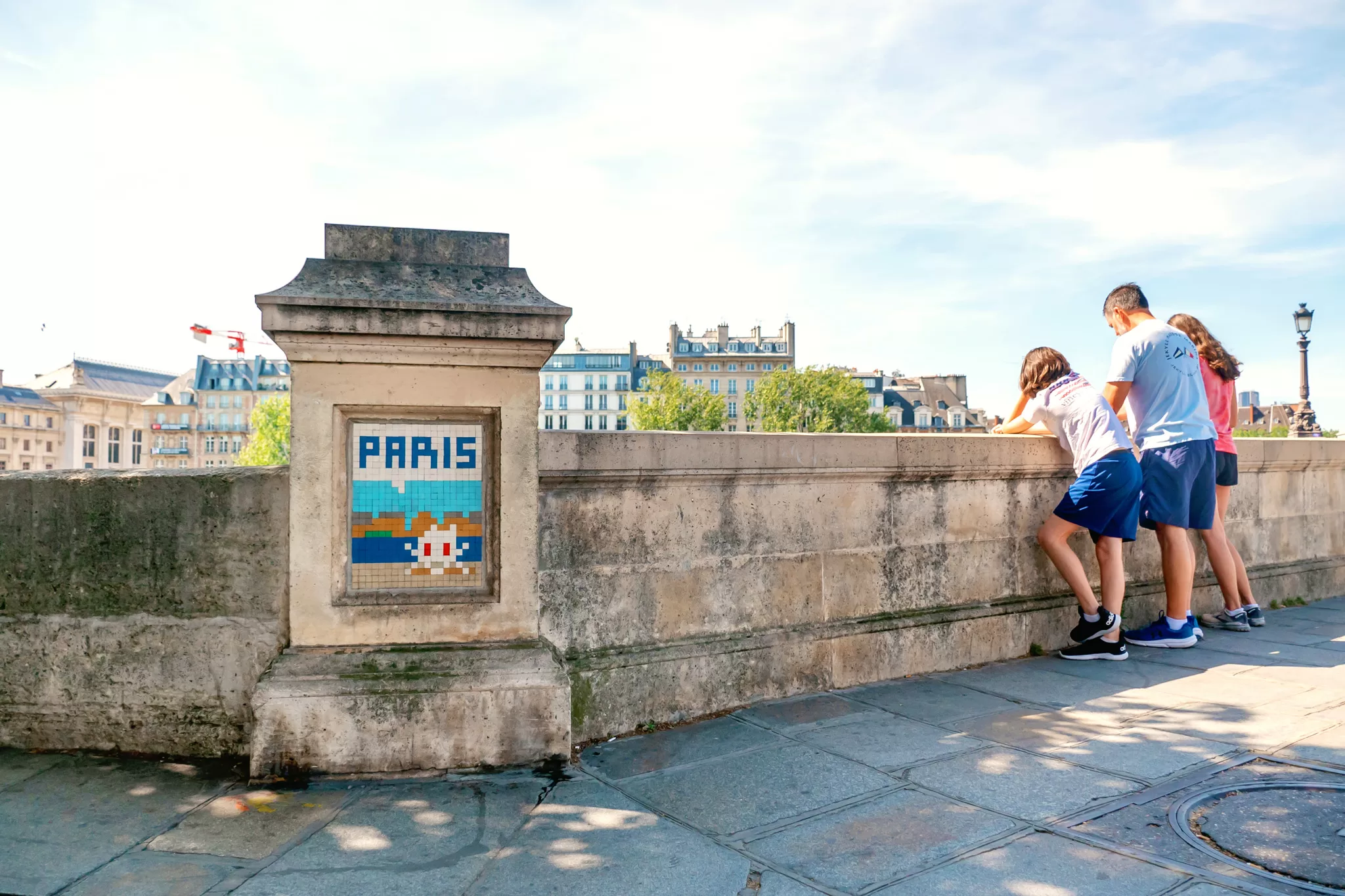 a family looking out onto the Seine River in Paris. They are standing on a bridge.