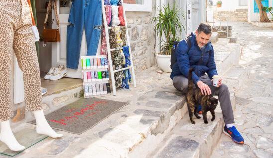 photo of a man petting a cat in greece