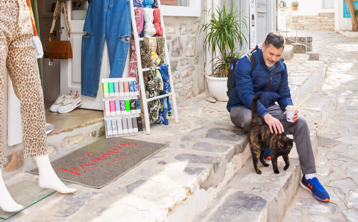 photo of a man petting a cat in greece
