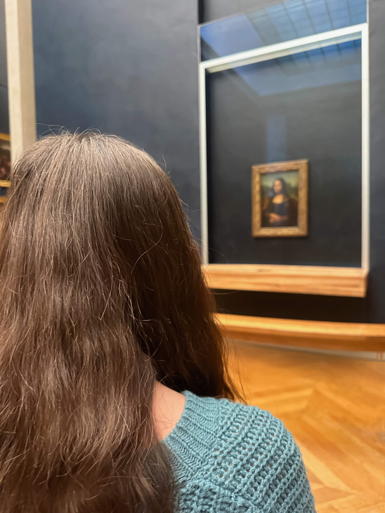 Girl looking at the mona lisa at the Louvre