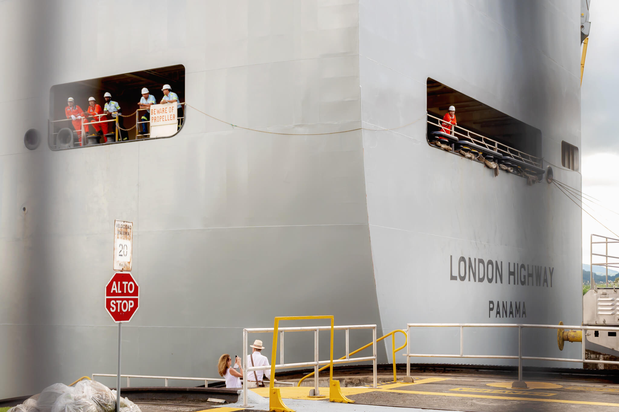 a couple on a panama canal tour while people in the ship wave at them 