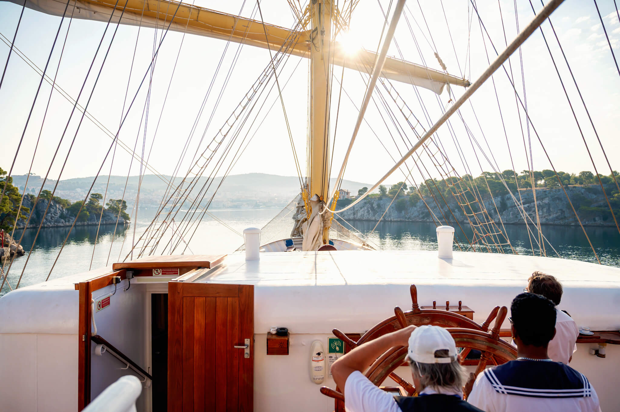 Star Clippers Royal Clipper Day 2 Sibenik Croatia 09 • Our Little Lifestyle Sailing yacht deck with numerous rigging lines overhead, sun glare over a calm coastal inlet in the background.